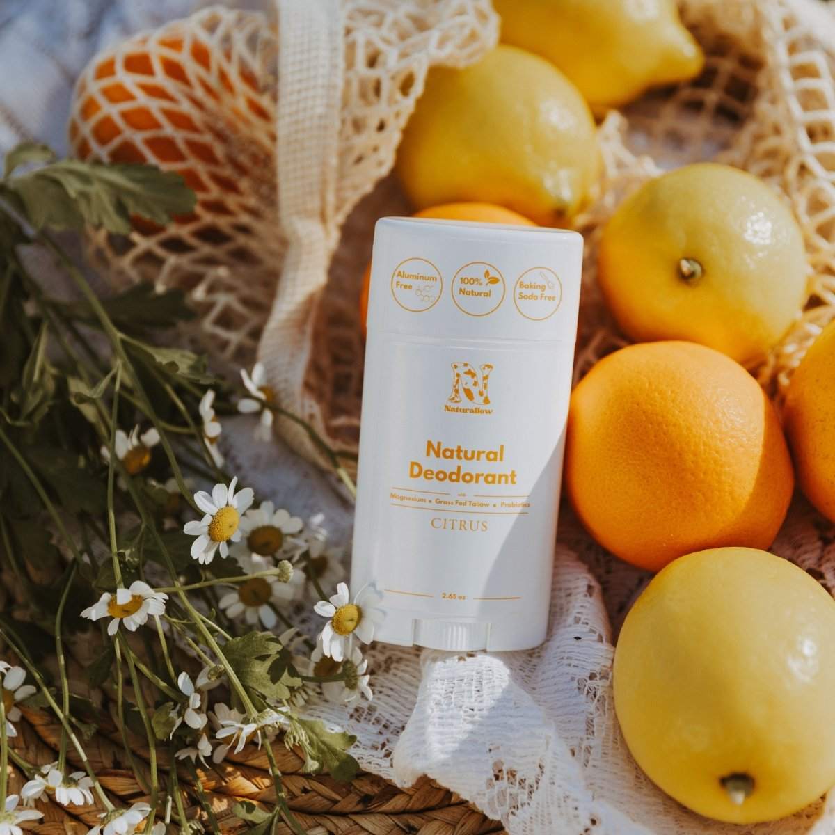Naturallow's Citrus Natural Deodorants leaning against a pile of citrus fruit