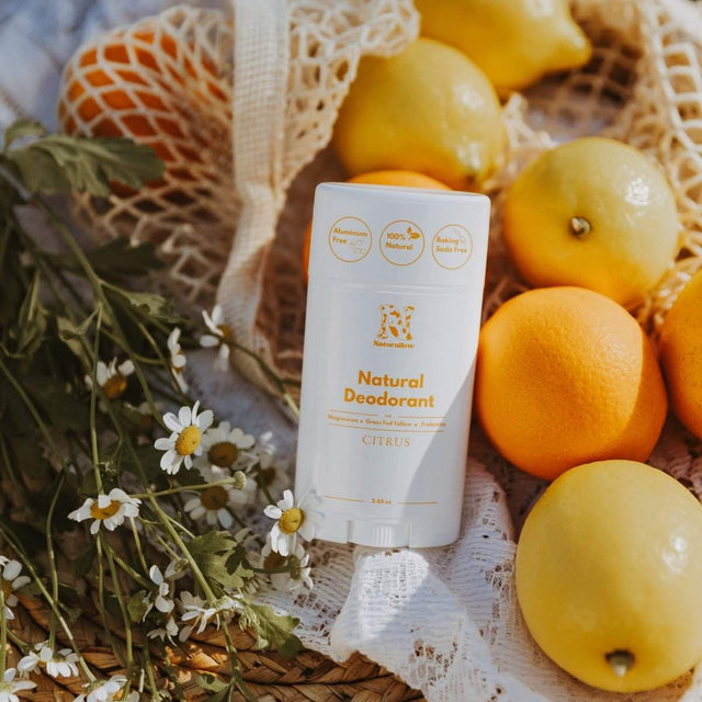 Naturallow's Citrus Natural Deodorants leaning against a pile of citrus fruit