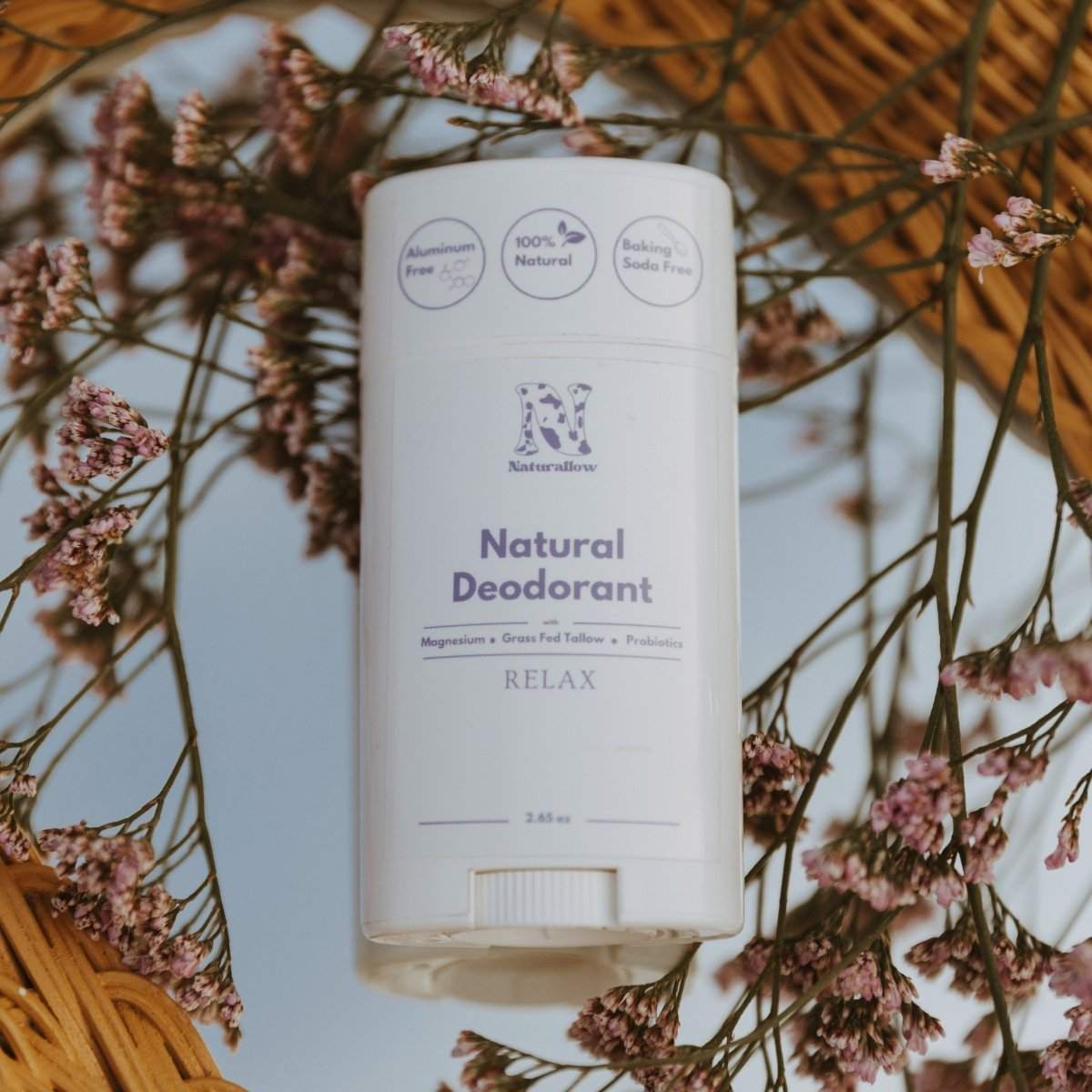 Naturallow's Relax Natural Deodorants lying down on a mirrored surface with floral around it