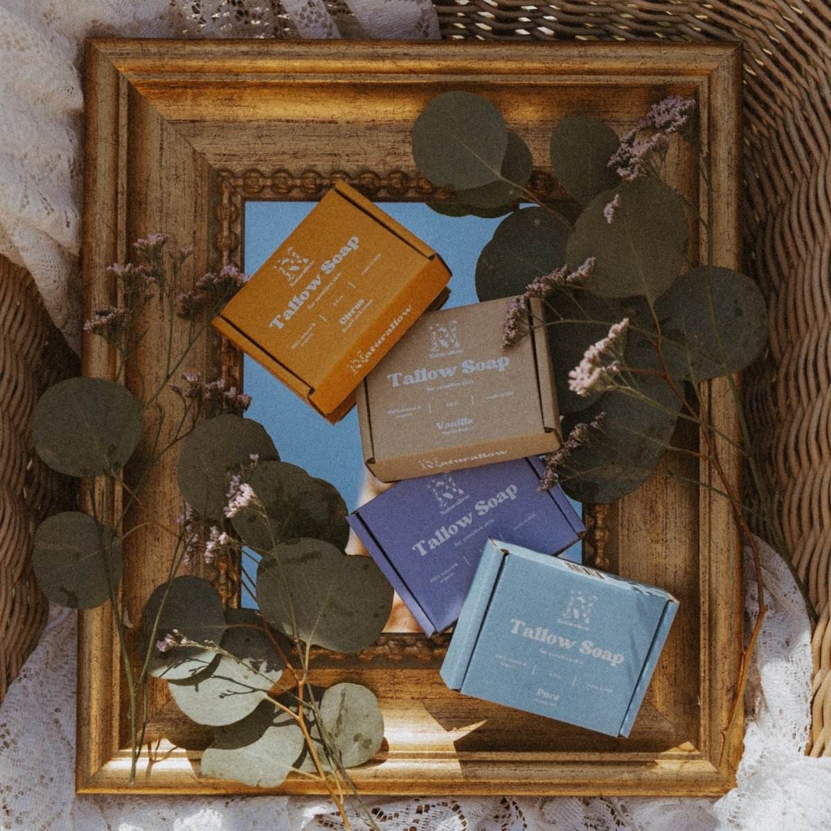 Naturallow Tallow Soap variants sitting on a mirror surrounded by foliage