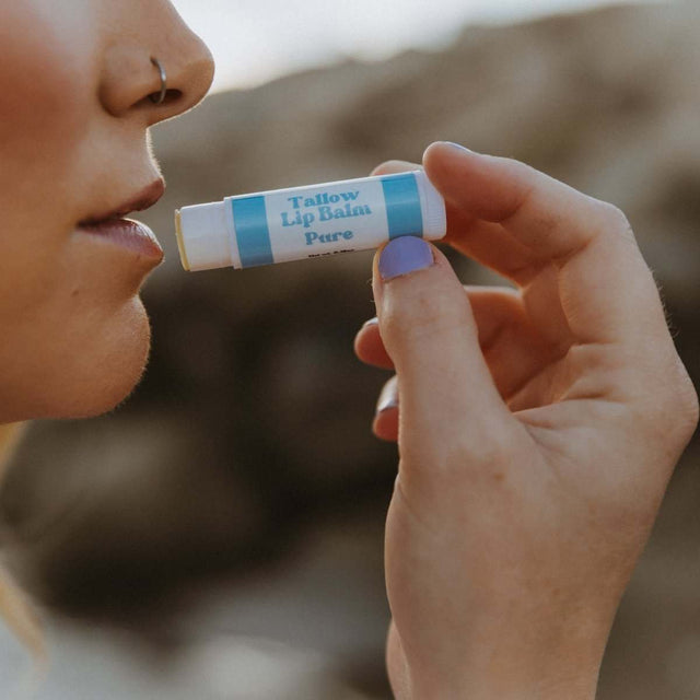 A side-view closeup of a woman's lips as she applies Naturallow's Pure Unscented Tallow Lip Balm to her lips