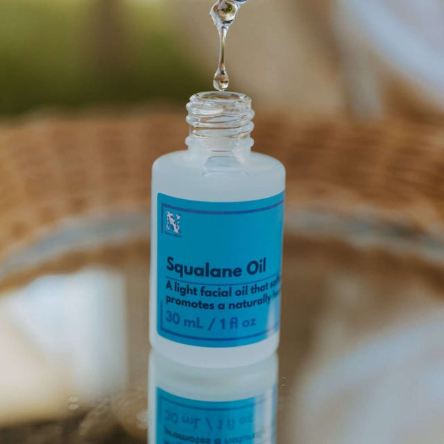 Naturallow's Organic Squalane Oil bottle sitting in with the cap off on a mirrored surface