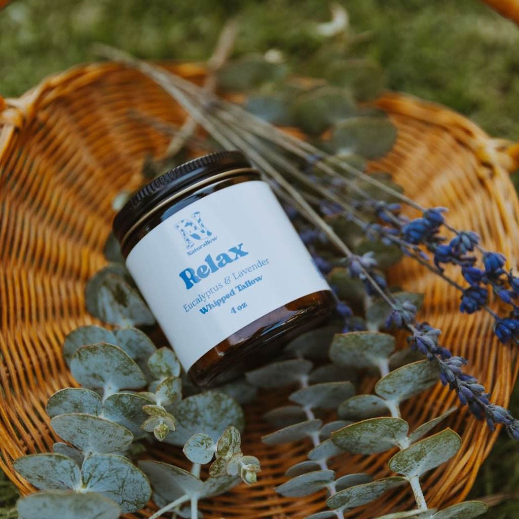 Naturallow's Relax Whipped Tallow Moisturizer for dry skin in front of eucalyptus leaves on a woven basket