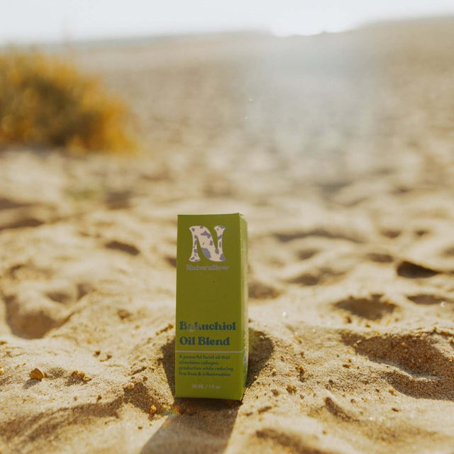 Naturallow's Bakuchiol Facial Oil Retinol Alternative box sitting in the sand with a beach horizon in the background