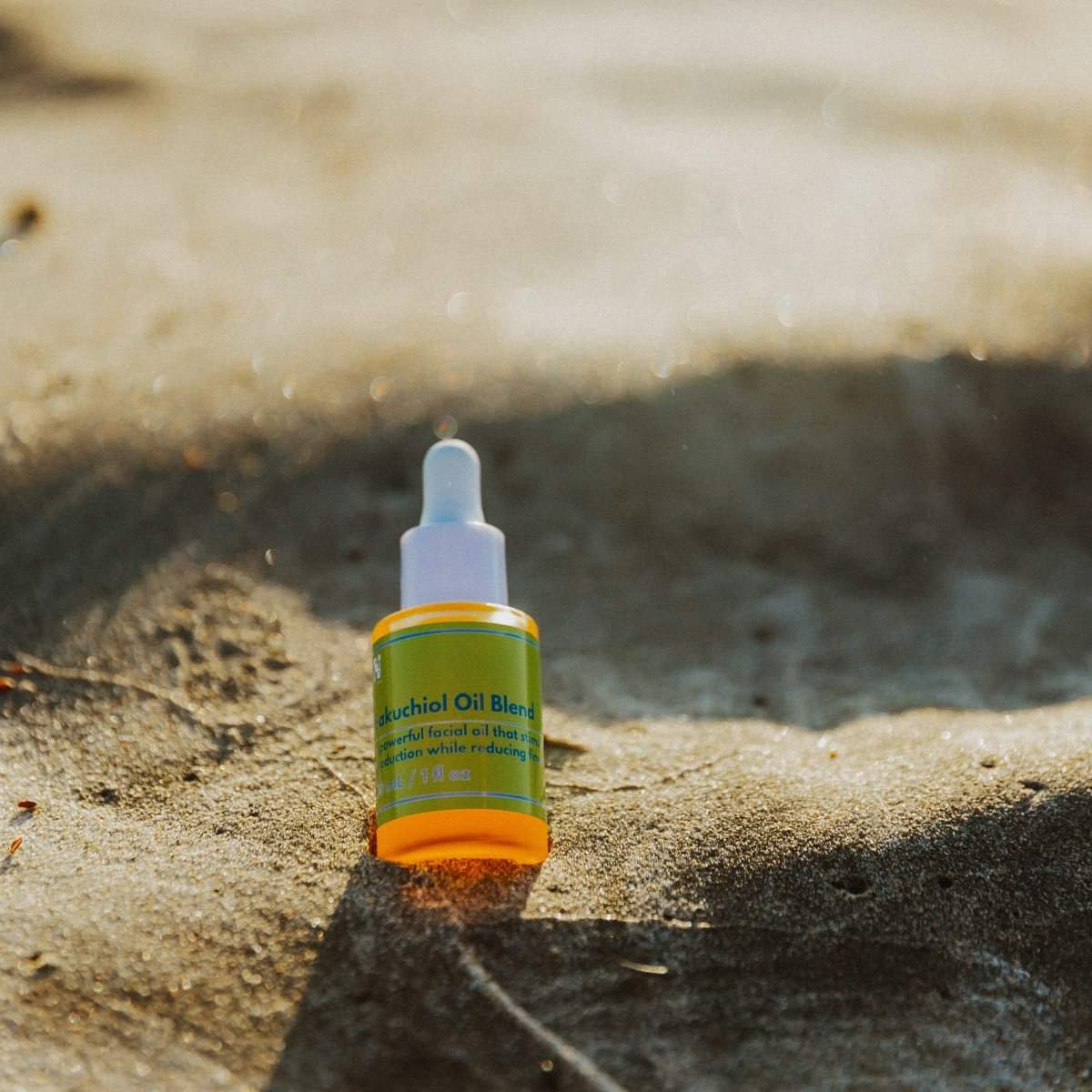 Naturallow's Bakuchiol Facial Oil Retinol Alternative bottle lying in the sand with a beach horizon in the background