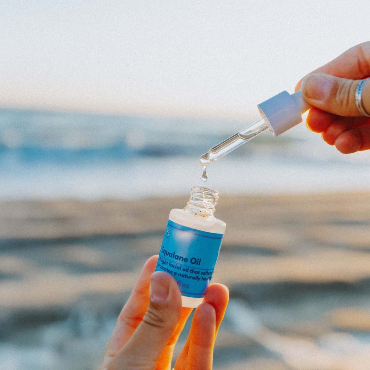 Naturallow's Organic Squalane Oil with the dropper being held up against the horizon