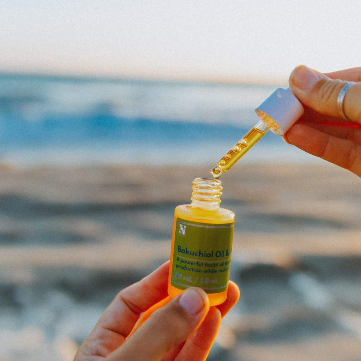 Naturallow's Bakuchiol Facial Oil Retinol Alternative with a dropper against a beach horizon