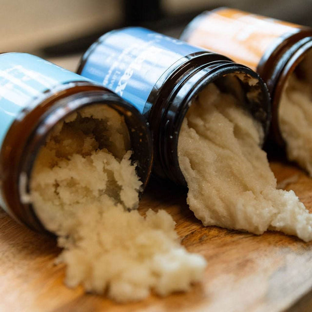 A front-view of Naturallow's Sugar Scrub Jars lined up next to each other and spilling out