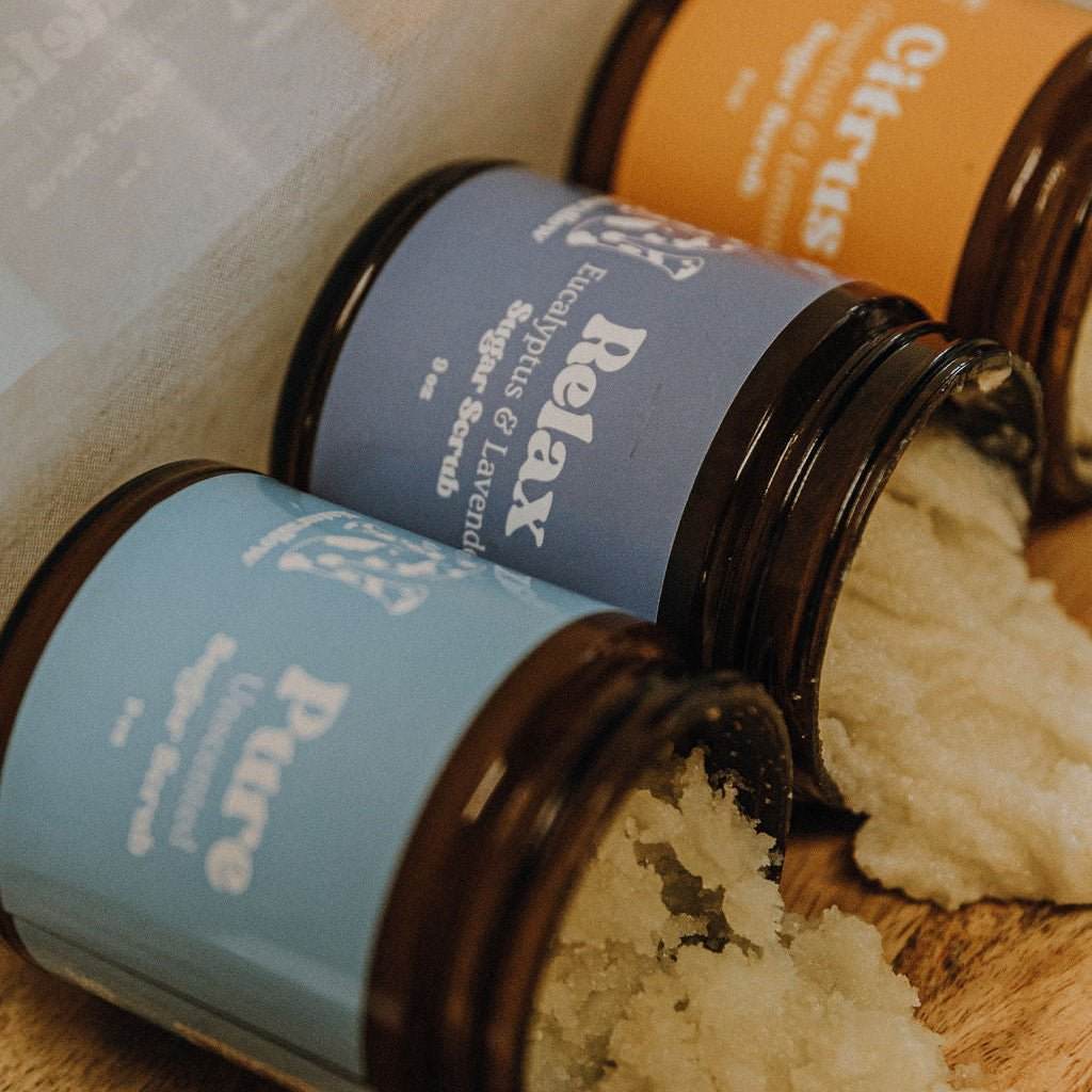 Naturallow's Sugar Scrub Jars lined up next to each other and spilling out