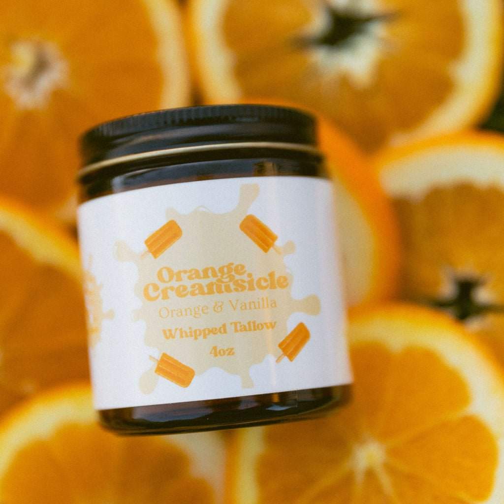Naturallow's Orange Creamsicle Whipped Tallow Moisturizer jar on a pile of citrus slices