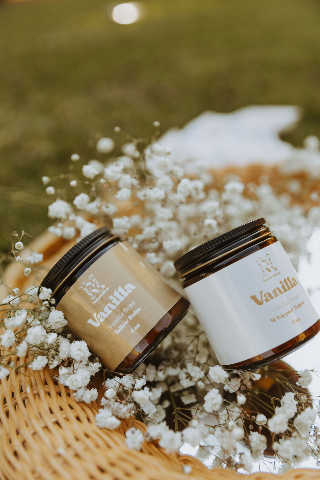 Two jars of Vanilla Cream on a woven mat with white flowers and blurred green background