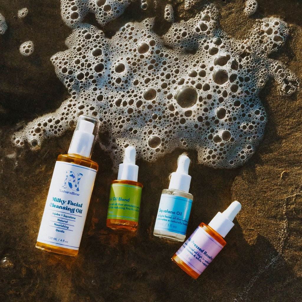Naturallow's 3-Step Barrier Repair Bundle product image consisting of facial oil bottles laying in the shallow beach tide
