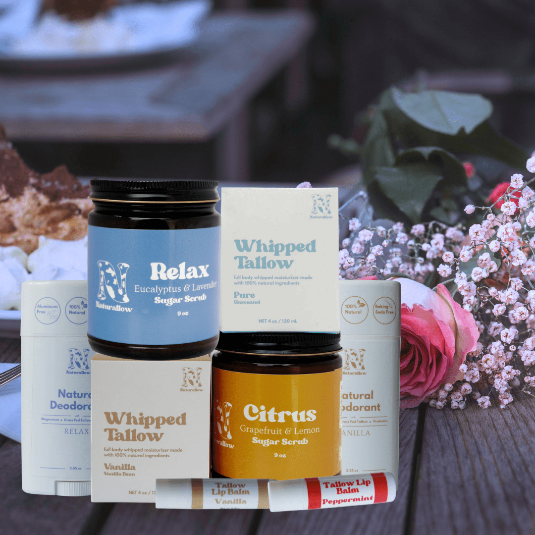 Collection of skincare and body care products on a wooden surface with flowers in the background.