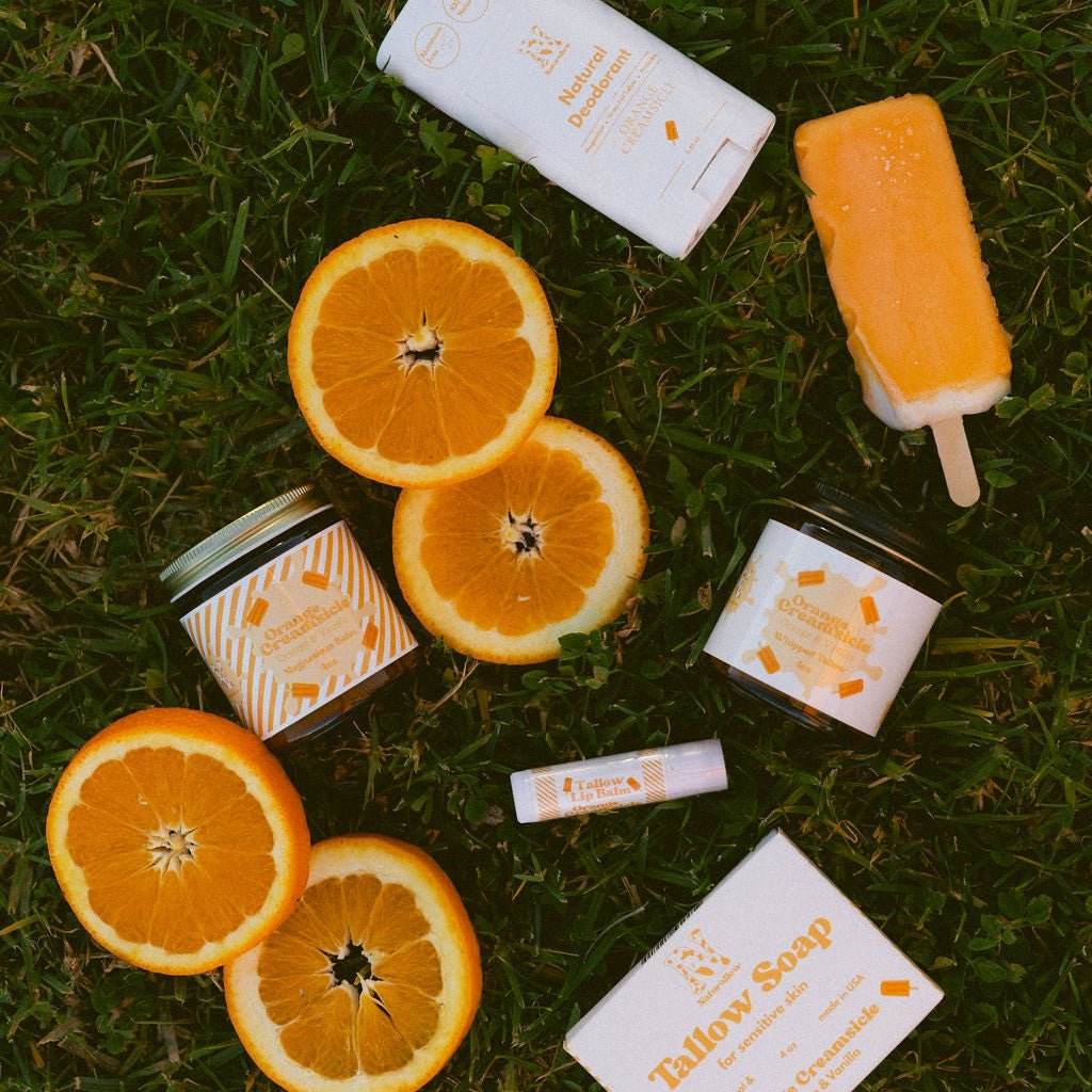 Naturallow's Orange Creamsicle Complete Collection in the grass with orange slices