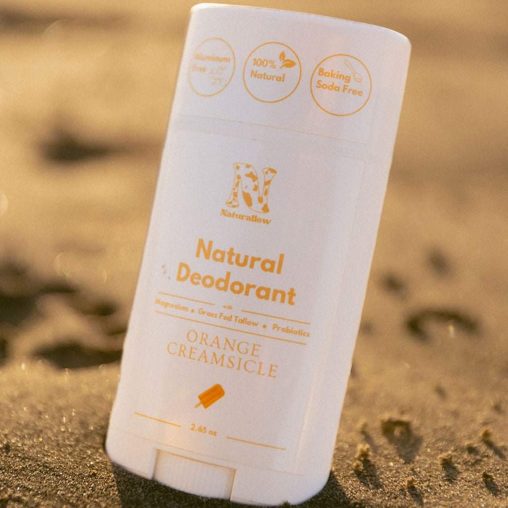 An up-close shot of Naturallow's Limited Edition Orange Creamsicle deodorant on a sandy beach