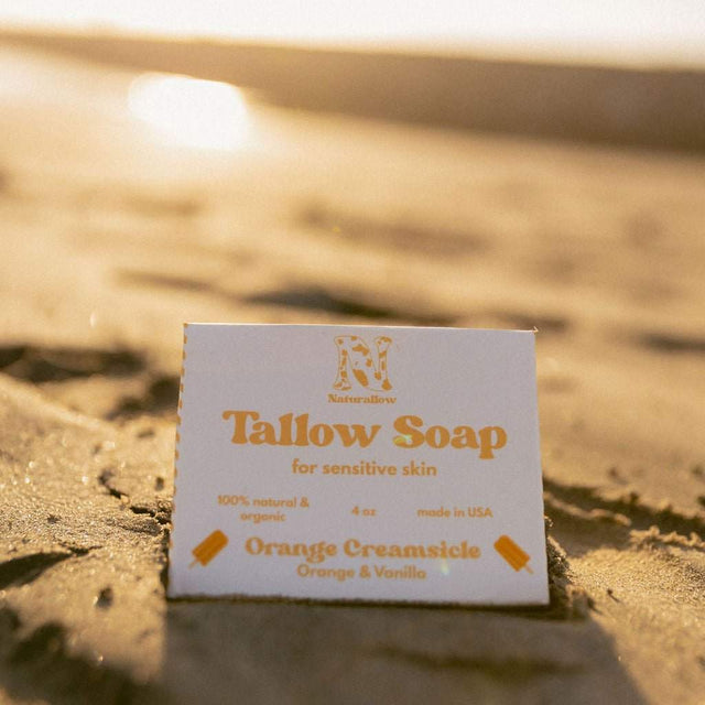 Naturallow's Limited Edition Orange Creamsicle tallow Soap box sitting in the sand with a sunset horizon in the background