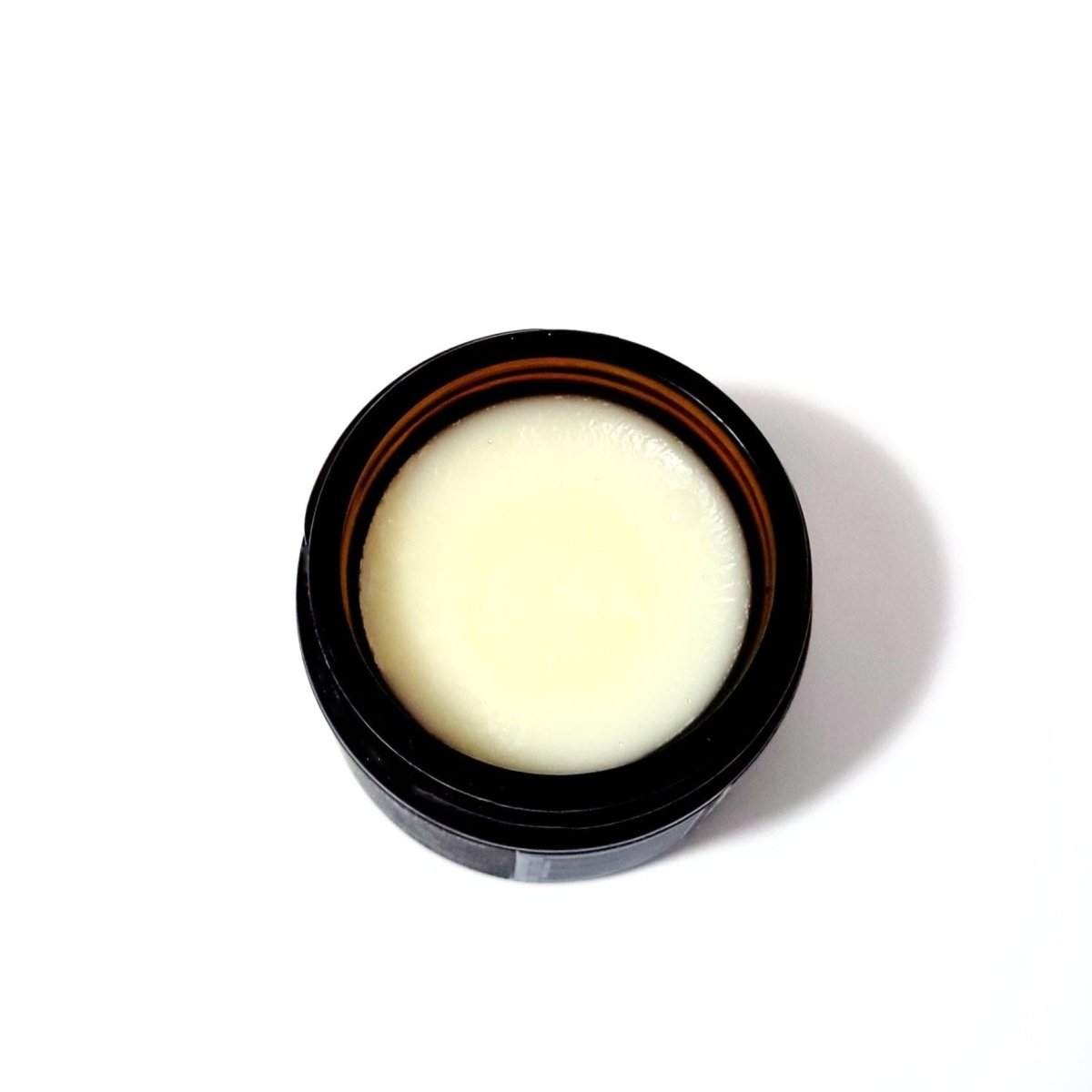 A top-down view of Naturallow's Tallow Body Balm Jar for dry skin on a white background revealing the smooth off-white tallow balm inside