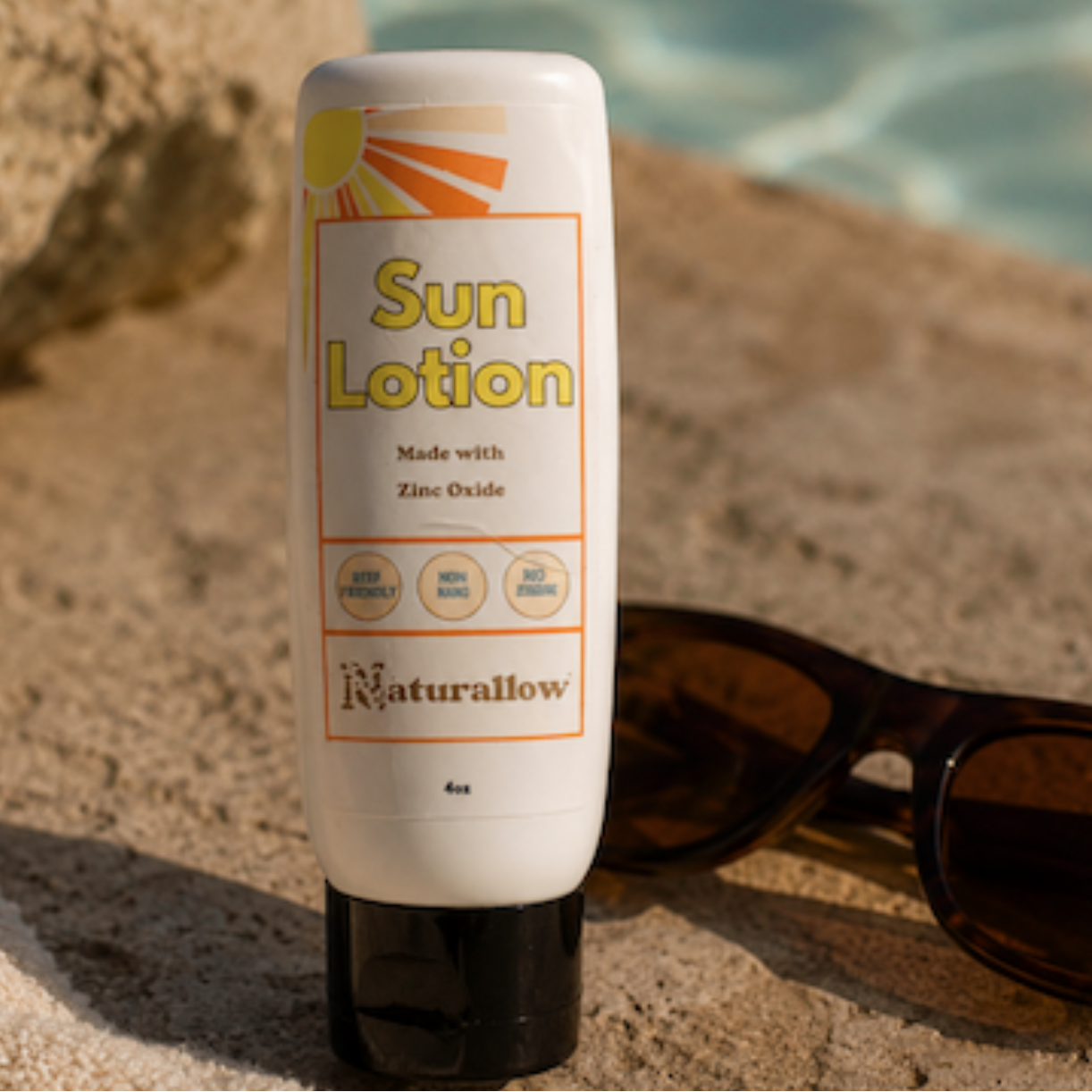 Naturallow Sun Lotion sitting by the pool with a pair of sun glasses
